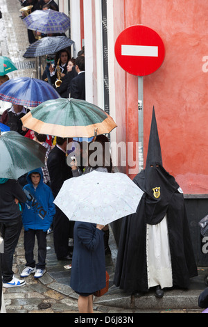 Büßer während der Semana Santa (Karwoche) entlang verregnete Straße, Sevilla, Andalusien, Spanien, Europa Stockfoto