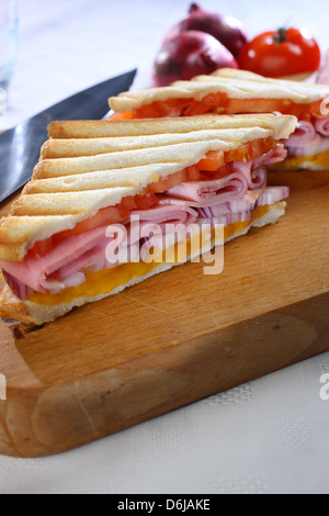 Schinken-Käse-Tomaten und roten Zwiebeln geröstet Sandwich auf hölzernen Steckbrett mit Messer Stockfoto