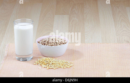 Ein Glas Sojamilch mit einer Schüssel von rohen Sojabohnen und Soja-Saatgut Stockfoto