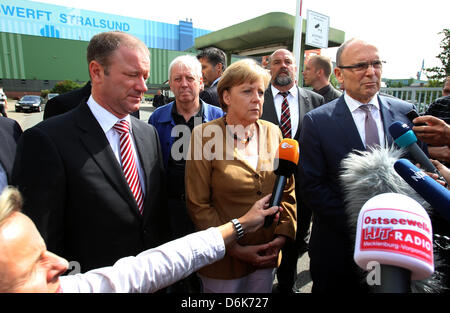 Bundeskanzlerin Angela Merkel, Premier of Mecklenburg-Western Pomerania Erwin Sellering (R) und Manager von P + S-Petkumer in Stralsund und Wolgast Rüdiger Fuchs (L) geben ein Statement am Eingang der Volksweft-Werft in Stralsund, Deutschland, 21. August 2012. Merkel nahm Teil in einer Besprechung über die Zukunft der Schiffbau-Unternehmen, wo waren Vertreter der Medien nicht gestattet. Stockfoto