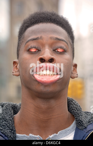 Junger Mann im Union Square Park in New York City, so dass eine lustiges Gesicht kaufen curling seine Lippen und seine Augenlider umkrempeln. Stockfoto