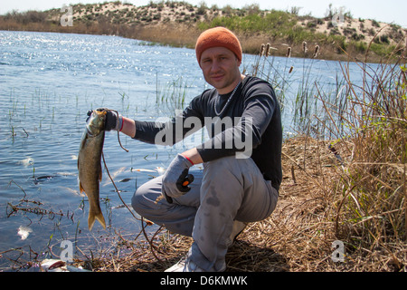 Glücklich glücklich Fischer hielt eine großen Karpfen am Fluss. Am frühen Morgen über die Fischerei Stockfoto
