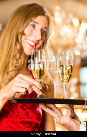 Kellner serviert Sektgläser auf einem Tablett in ein feines Restaurant und Frau nimmt ein Glas Stockfoto
