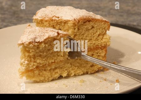 Eine Scheibe Zitrone Biskuit ist mit einer Kuchengabel geschnitten wird. Stockfoto