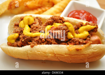 Chili-Hund und Senf mit Ketchup und Pommes frites im Hintergrund Stockfoto