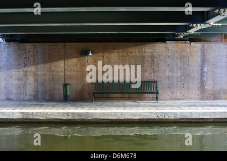 Eine leere Parkbank unter einer Brücke, an einem Fluss in Oklahoma City, Oklahoma. Stockfoto