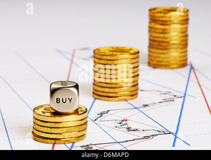 Würfel Cube mit Word kaufen, Stapel von Goldmünzen und neuesten Trenddiagramm als Hintergrund. Erfolgreiches Handeln. Selektiven Fokus Stockfoto