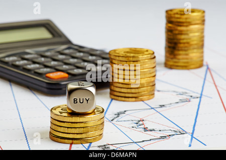 Steigenden Stapel von Münzen, die Würfel Cube mit dem Wort kaufen, Rechner auf finanzielle Diagramm Stockfoto