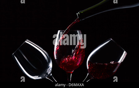 Flaschen und Gläser mit Rotwein auf einem schwarzen Hintergrund Stockfoto