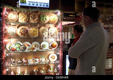 Hong Kong, China, Männer sind mit einer Vitrine mit dem Angebot eines Restaurants konfrontiert. Stockfoto