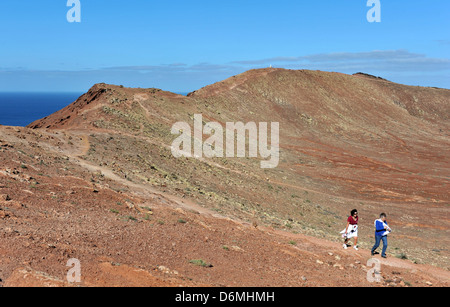 Zwei Damen gehen auf Vulkan, Montana Roja, ein beliebtes Ziel für Urlauber in Playa Blanca, Lanzarote. Stockfoto