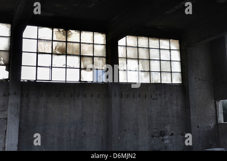 Zerbrochene Fensterscheiben und Betonwand in verlassenen Fabrik innen. Stockfoto