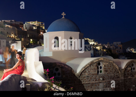 Griechischen Dame saß auf Mauer nahe orthodoxe Kirche, Nachtszene, Dorf Oia, Santorini, Griechenland Stockfoto