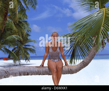 Junge Frau sitzt auf Palme, Kuda Bandos, Republik Malediven, Kaafu Atoll, Bandos Island Stockfoto