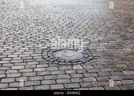 Alte Runde Stahl Kanalisation Kanaldeckel auf der gepflasterten Straße Stockfoto