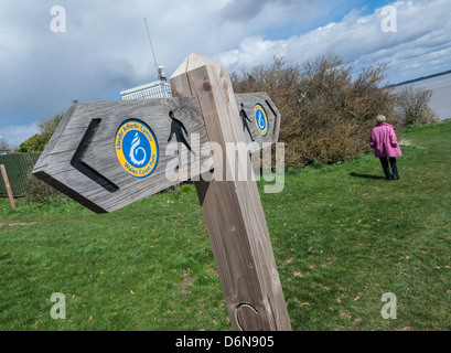 ZEICHEN AUF WALES COAST PATH IN DER NÄHE VON BLACK ROCK MIT WALKER IN FERNE Stockfoto