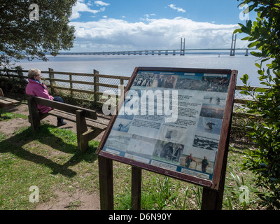 WALES COAST PATH IM SCHWARZEN ROCK MIT WALKER SITZEND AUF BANK UND ZWEITE SEVERN CROSSING IM HINTERGRUND. Stockfoto