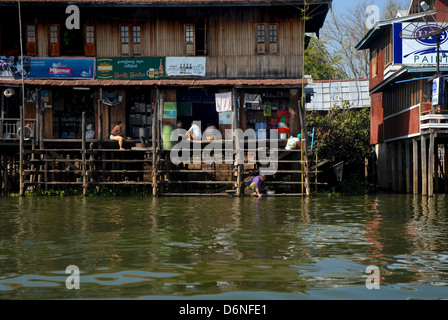 Ladenbesitzer außerhalb Ladenzeile gebaut auf Pfählen über dem Wasser des Inle-See, Myanmar Burma Stockfoto