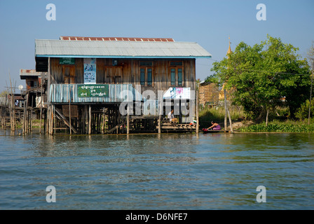 Frauen, die Wäsche draußen Tradition Holzgebäude, gebaut auf Pfählen über dem Wasser des Inle-See, Myanmar Burma Stockfoto