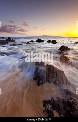 Sonnenuntergang und Wellen über Lavafelsen am Oneloa Strand oder "Big" Strand in Makena State Park, Maui, Hawaii Stockfoto