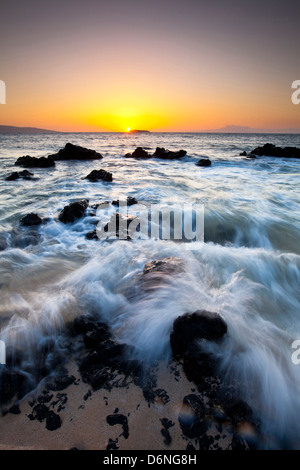 Sonnenuntergang und Wellen über Lavafelsen am Oneloa Strand oder "Big" Strand in Makena State Park, Maui, Hawaii Stockfoto