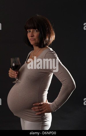 Freiburg, Deutschland, eine schwangere Frau mit einem Glas Rotwein Stockfoto