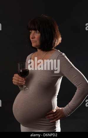 Freiburg, Deutschland, eine schwangere Frau mit einem Glas Rotwein Stockfoto