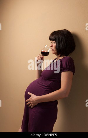 Freiburg, Deutschland, eine schwangere Frau mit einem Glas Rotwein Stockfoto