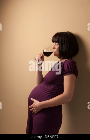 Freiburg, Deutschland, eine schwangere Frau mit einem Glas Rotwein Stockfoto