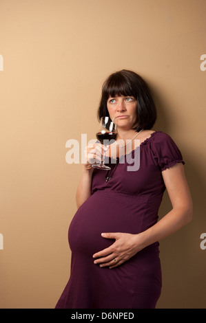 Freiburg, Deutschland, eine schwangere Frau mit einem Glas Rotwein Stockfoto