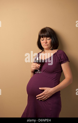 Freiburg, Deutschland, eine schwangere Frau mit einem Glas Rotwein Stockfoto