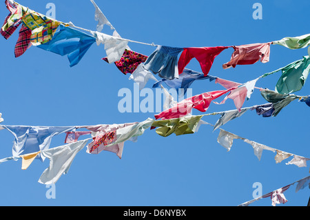Eine Gruppe von farbigen t-Shirts auf einer Wäscheleine vor blauem Himmel Stockfoto