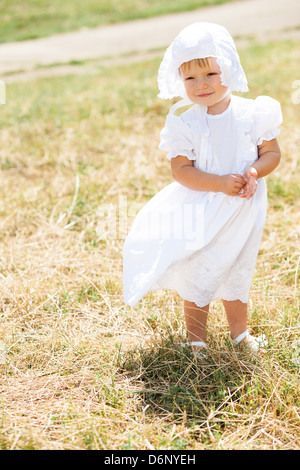 kleine Mädchen steht in einem Feld im weißen Kleid Stockfoto