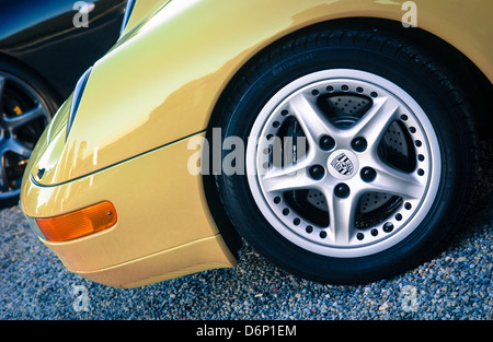 Nahaufnahme der Vorderseite des gelben Porsche-Autos mit Logo auf dem Rad Stockfoto