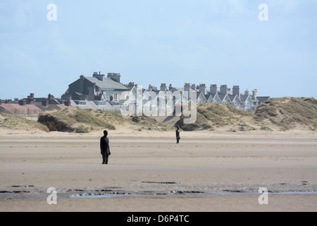 Antony Gormley woanders Statuen am Strand von Crosby mit Häusern in der backgroumd Stockfoto