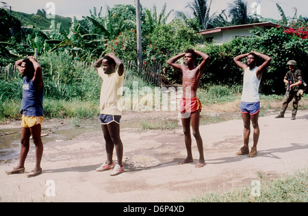 82nd Airborne Division Soldat bewacht aufgenommenen Mitglieder der Völker revolutionäre Armee während der Invasion von Grenada, unter dem Codenamen Operation Urgent Fury 25. Oktober 1983 in St. Georges, Grenada. Die Invasion begann am 25. Oktober 1983 und wurde die erste größere militärische Aktion von den Vereinigten Staaten seit dem Ende des Vietnam-Krieges. Stockfoto