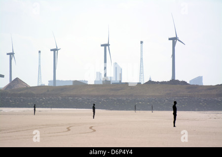 Antony Gormley woanders Statuen am Strand von Crosby mit einem Windpark im Hintergrund Stockfoto