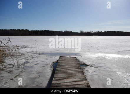 zugefrorenen See und ein Dock in Finnland. Eis auf dem See beginnen zu schmelzen. Stockfoto