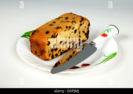 Sultana Früchtekuchen auf einem weißen Teller und einem Tortenmesser. Stockfoto