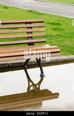 Eine Bank und Reflexion im Park nach dem Regen Stockfoto