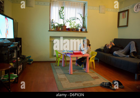 Wroclaw, Polen, sieht eine Mädchen bei einer Zeichentrickserie im Fernsehen, ihr Vater auf dem sofa Stockfoto