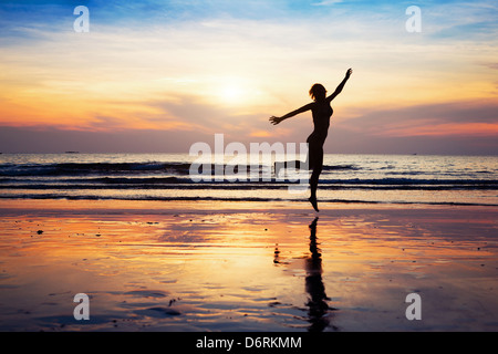 Frauen-Silhouette springen am Strand bei Sonnenuntergang