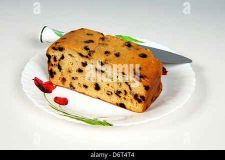 Sultana Früchtekuchen auf einem weißen Teller mit einem Tortenmesser nach hinten. Stockfoto