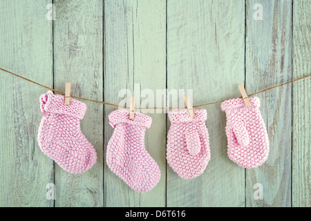 Rosa Baby Mädchen Socken und Handschuhe auf Vintage Wäscheleine auf grün Vintage Holz-Hintergrund Stockfoto