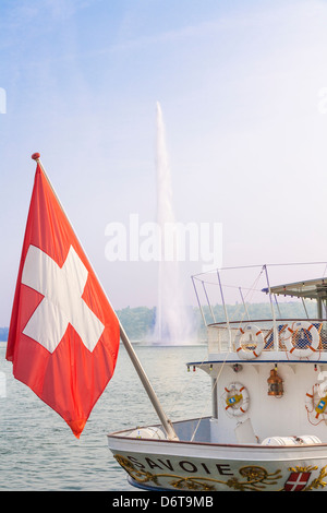 Schweizer Nationalflagge auf einem Dampfschiff in Genf mit dem Jet d ' Eau am Genfer See (Lac Léman) und blauer Himmel Stockfoto