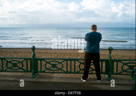 Mann, der eine Geländer, Blick auf See, Brighton, UK Stockfoto
