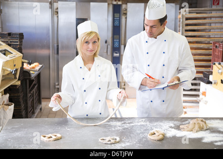 Ausbilder in der Bäckerei Lehre Lehrling, wie eine Brezel aus Teig zu bilden Stockfoto