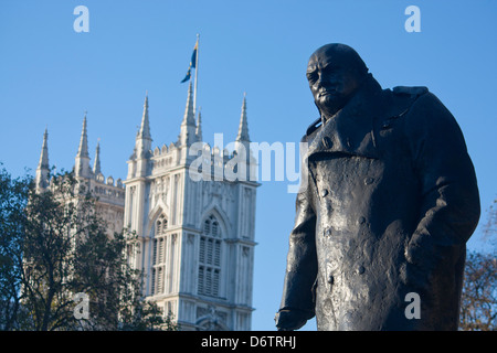 Statue von Sir Winston Churchill im Parliament Square mit Türmen der Westminster Abbey in London England UK Hintergrund Stockfoto