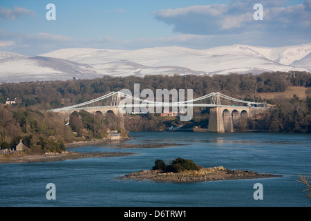 Thomas Telfords Menai Hängebrücke über die Menaistraße mit schneebedeckten Berge von Snowdonia hinter Anglesey North Wales UK Stockfoto