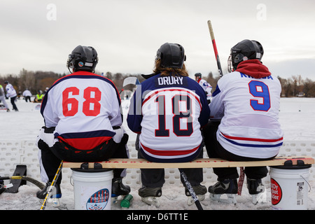 Teich-Hockey-Spieler sehen die Aktion von der Mannschaftsbank während eines Spiels bei der US-Pond Hockey Meisterschaften auf See Nokomis. Stockfoto